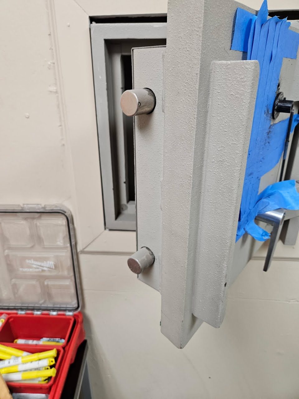 Wall safe with its door open, showing the round steel locking bolts